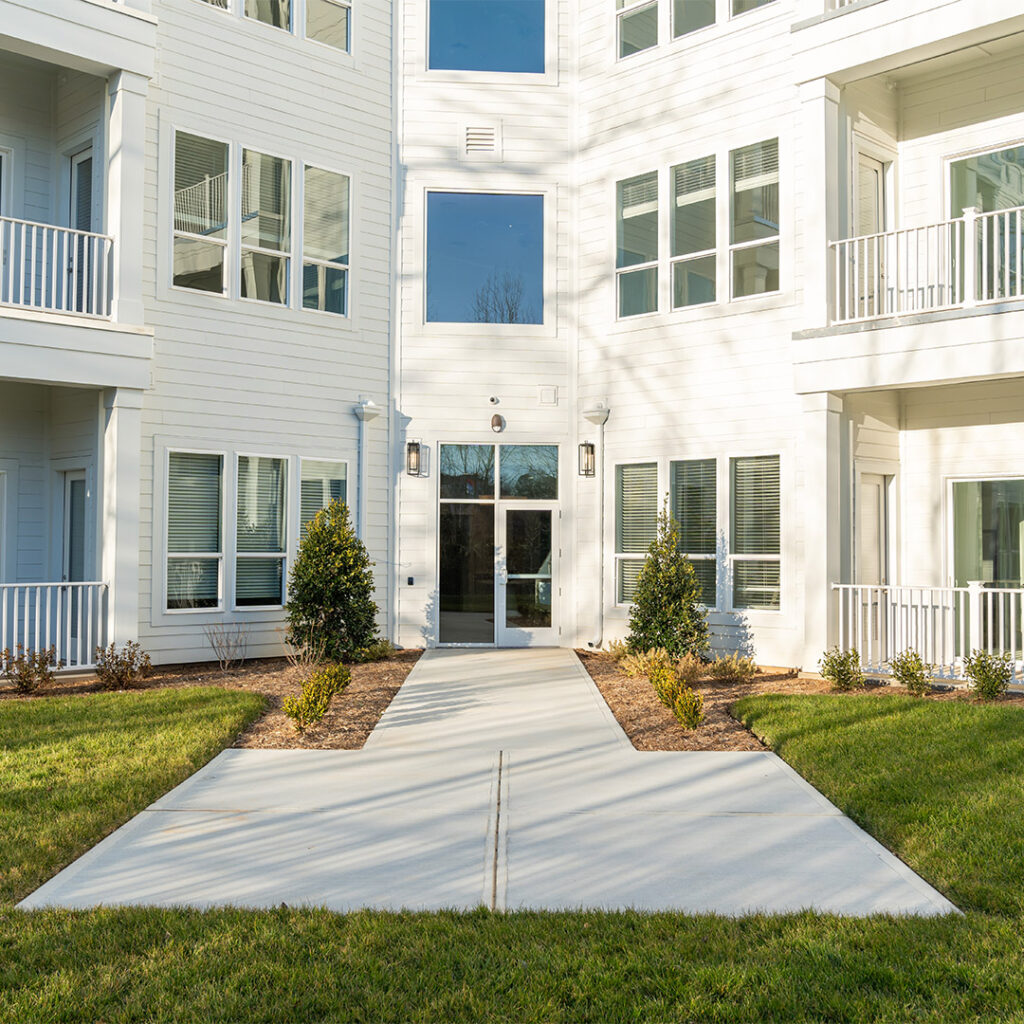 Sunny exterior of Cameryn Elise, luxury apartments for seniors, featuring manicured lawns, large balconies, and white siding