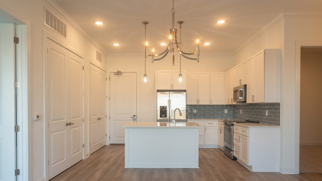 Kitchen at Cameryn Elise, luxury apartments for seniors, with blue colored tile backsplash, chandelier, kitchen island, stainless appliances