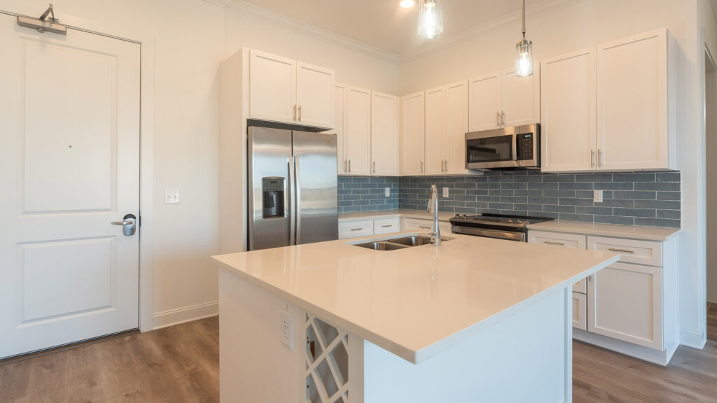 Kitchen at Cameryn Elise, luxury apartments for seniors, with blue colored tile backsplash, chandelier, kitchen island, stainless appliances