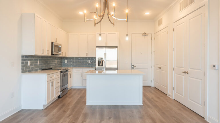 Kitchen at Cameryn Elise, luxury apartments for seniors, with blue colored tile backsplash, chandelier, kitchen island, stainless appliances